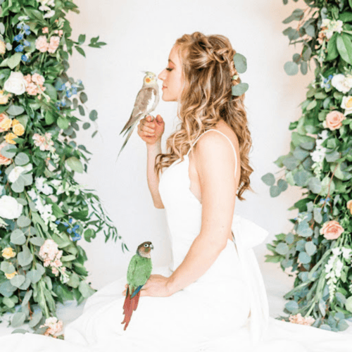 woman standing in the middle of flower backdrop with birds