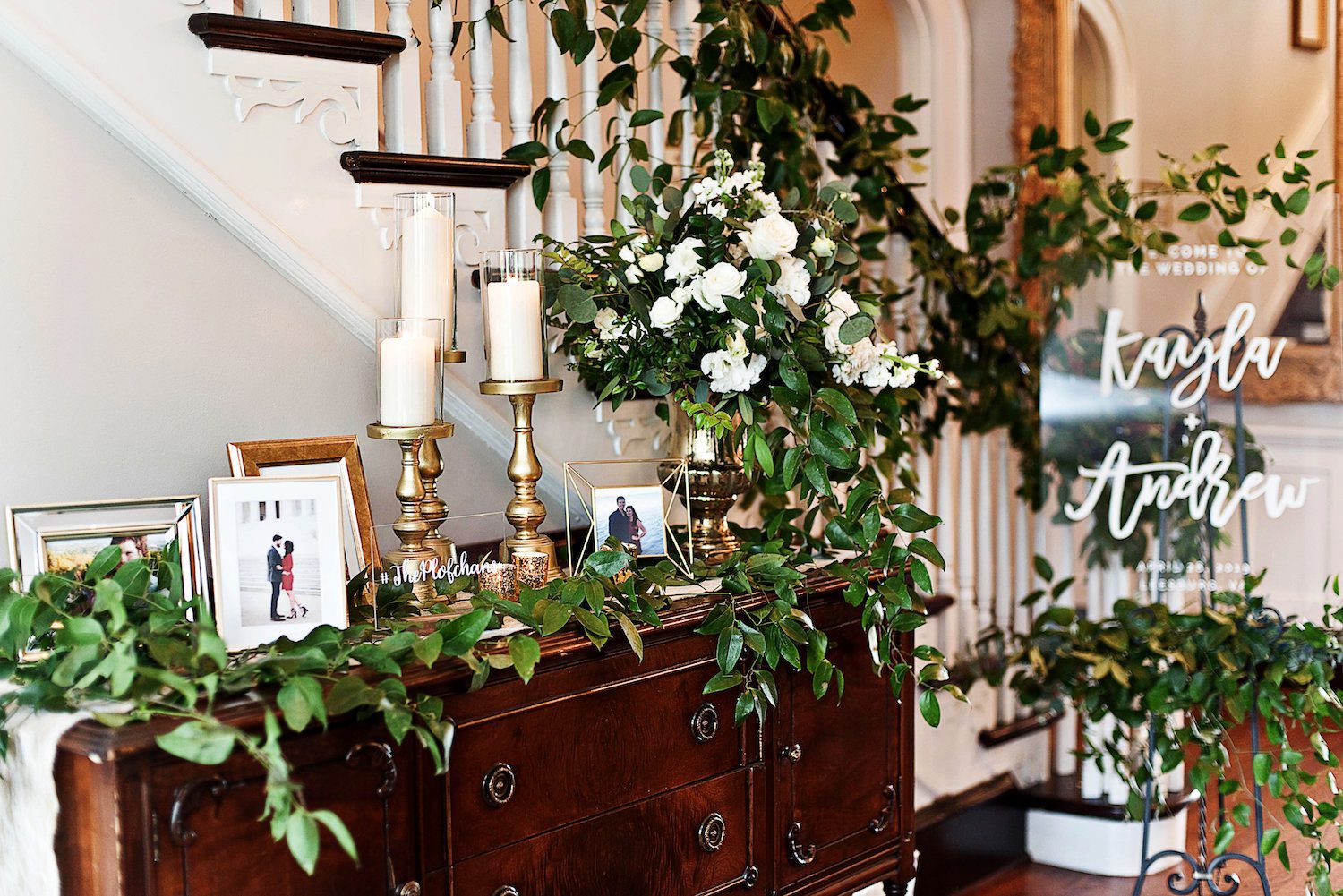 The entryway table, stairwell and welcome sign with greens and floral included personal framed photos.