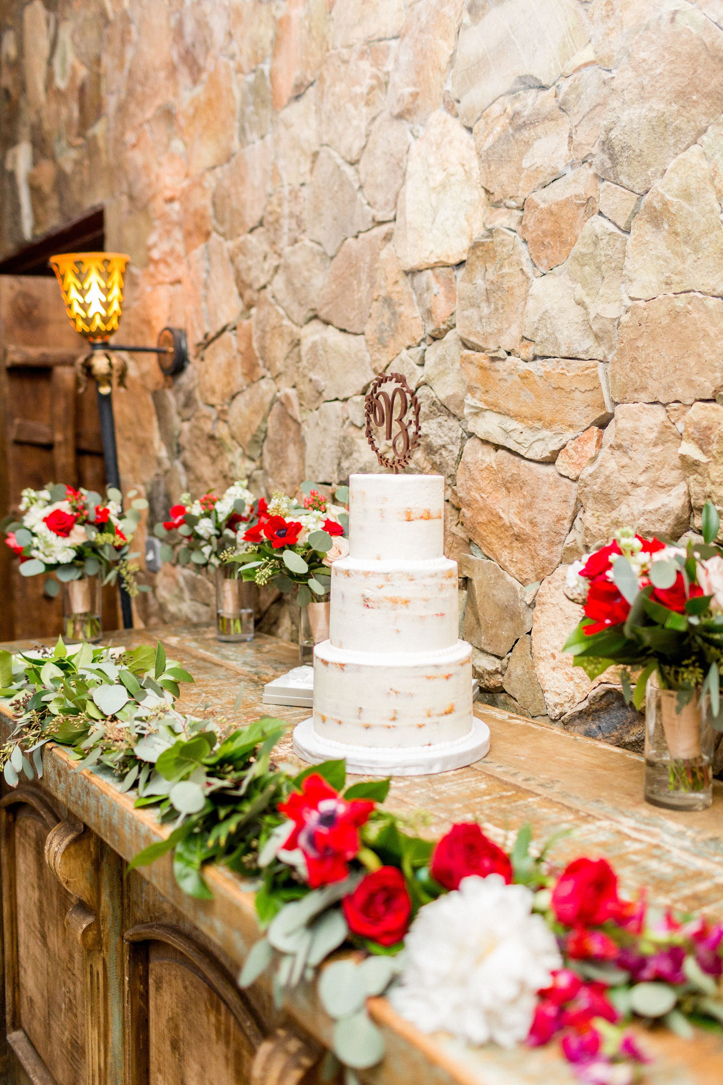 Greenery blends to flowers in this mantle spray at Stone Tower Winery. The cake was surrounded by bridal bouquets in cylinders. Photography by Candice Adele.