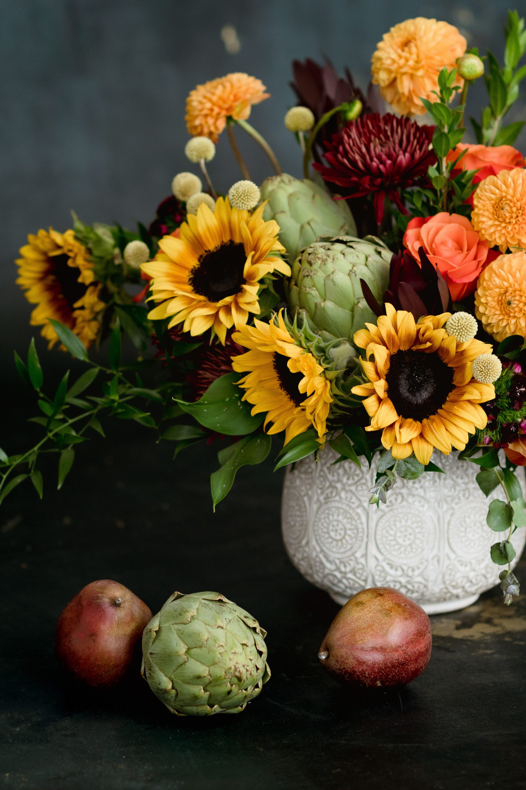 pot of flowers on a tablet next to a few pieces of fruit pot of flowers on a tablet next to a few pieces of fruit